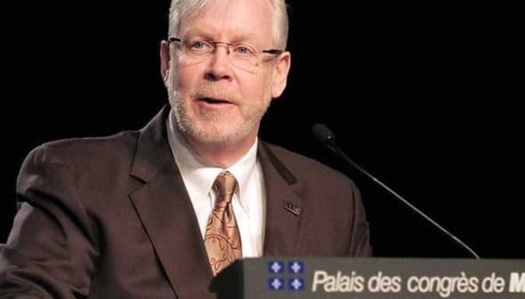 A man with glasses speaking at a podium with a sign that reads 'Palais des congrès de Montréal'. - Olive Oil Times