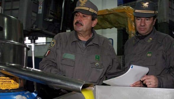 Two officials in military uniforms observing an oil extraction process in a facility. - Olive Oil Times