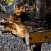 Close-up of an olive harvesting machine with olives on the ground beneath it. - Olive Oil Times