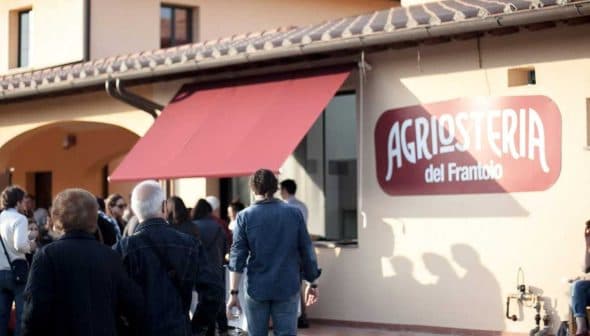 People walking towards the entrance of Agrilosteria del Frantoio with a red awning. - Olive Oil Times