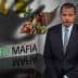 A man in a suit standing next to a graphic titled 'Agro Mafia' with food items and a glass of wine. - Olive Oil Times