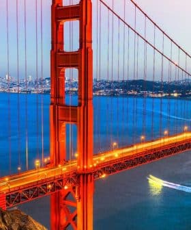 Golden Gate Bridge illuminated at sunset with a city skyline in the background. - Olive Oil Times