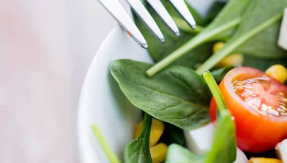 Bowl of fresh salad containing spinach, cherry tomatoes, corn, and feta cheese. - Olive Oil Times
