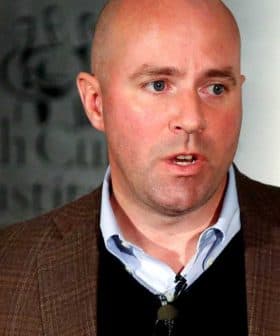 A man in a brown blazer speaking at the International Culinary Institute event. - Olive Oil Times