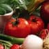 A variety of fresh vegetables and fruits including tomatoes, apples, and greens arranged together. - Olive Oil Times