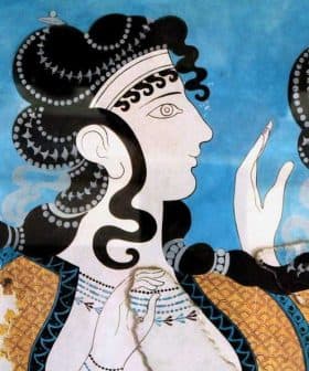 Ancient fresco showing three women with elaborate hairstyles and decorative clothing against a blue background. - Olive Oil Times