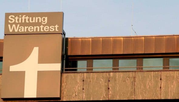 Signage of Stiftung Warentest displayed on a building exterior with a large plus symbol. - Olive Oil Times