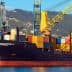 Cargo ship docked at a port with various colorful shipping containers stacked on board. - Olive Oil Times
