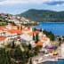 A coastal view of a Mediterranean town with red-roofed buildings and a blue sea. - Olive Oil Times