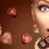Woman with light skin holding a piece of chocolate with various chocolate shapes around her. - Olive Oil Times