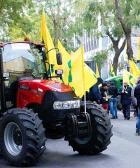 A red tractor parked on a street with yellow flags during a protest gathering. - Olive Oil Times