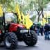 A red tractor parked on a street with yellow flags during a protest gathering. - Olive Oil Times