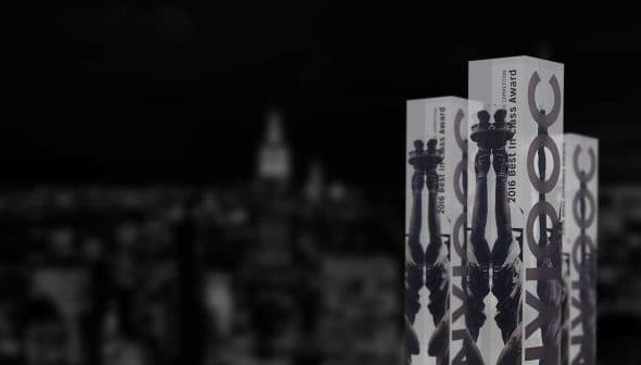 Three award bottles from the 2016 New York International Olive Oil Competition displayed against a blurred city background. - Olive Oil Times