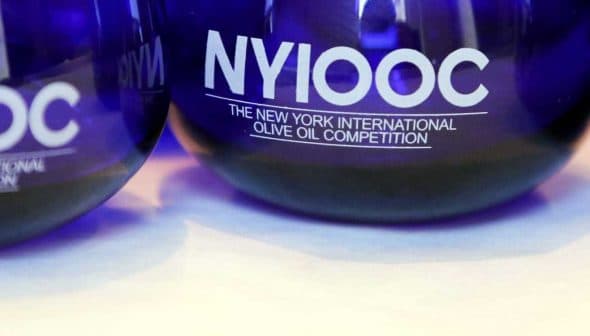 Blue glass awards for the New York International Olive Oil Competition with the text 'NYIOOC'. - Olive Oil Times