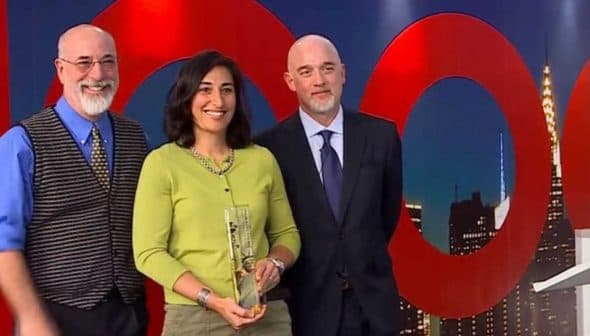 Three individuals at an award ceremony, one holding a trophy and smiling. - Olive Oil Times