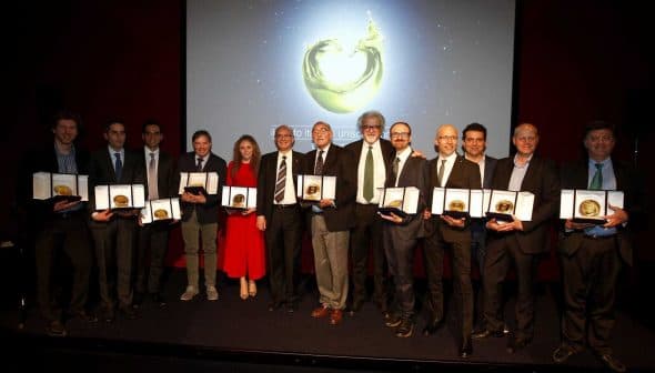Group of individuals holding awards during a ceremony with a backdrop display. - Olive Oil Times