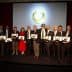 Group of individuals holding awards during a ceremony with a backdrop display. - Olive Oil Times