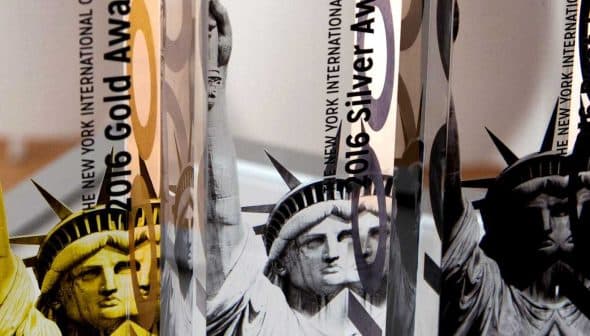 Three awards featuring the Statue of Liberty design with gold and silver text indicating the year and award type. - Olive Oil Times