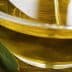 Close-up of a glass bowl filled with olive oil, surrounded by olives and olive leaves. - Olive Oil Times