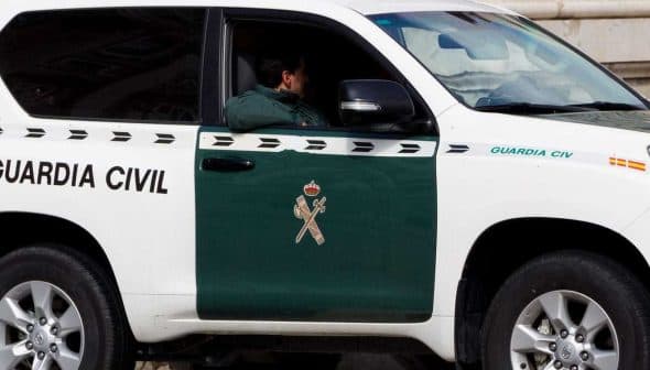 A Guardia Civil vehicle parked with a visible officer inside, featuring a green and white color scheme. - Olive Oil Times