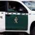 A Guardia Civil vehicle parked with a visible officer inside, featuring a green and white color scheme. - Olive Oil Times
