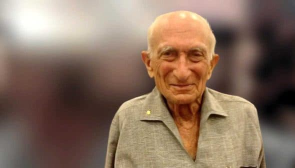 Elderly man with a bald head and gray shirt, smiling at the camera. - Olive Oil Times