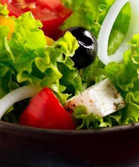 Bowl of fresh garden salad containing lettuce, tomatoes, olives, and onions. - Olive Oil Times