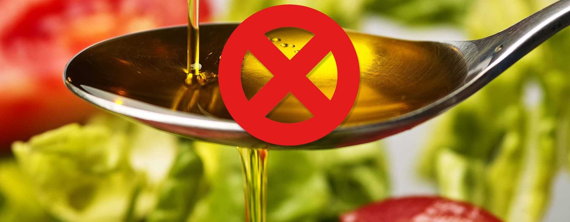 Spoon pouring olive oil with a red prohibition symbol overlaying the image. - Olive Oil Times