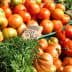 Assorted fresh tomatoes and vegetables displayed at a market stall with price tags. - Olive Oil Times