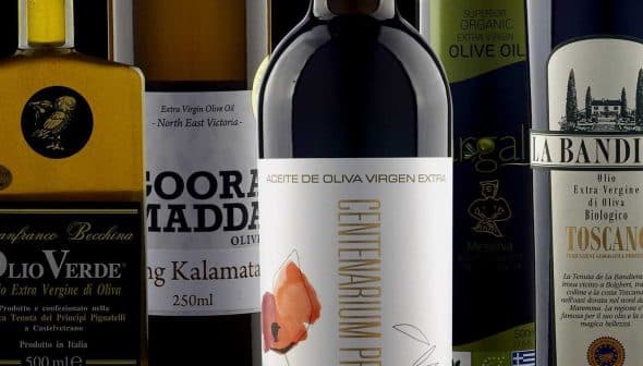 A collection of olive oil bottles featuring different brands and labels on a neutral background. - Olive Oil Times
