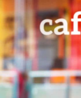 The word 'café' displayed on a glass window with a blurred background. - Olive Oil Times