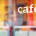 The word 'café' displayed on a glass window with a blurred background. - Olive Oil Times