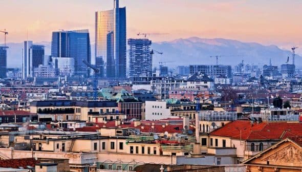 Panoramic view of Milan featuring modern skyscrapers and traditional buildings under a sunset sky. - Olive Oil Times