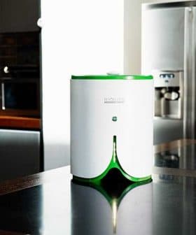 Compact white and green kitchen appliance with a button on top, placed on a dark countertop. - Olive Oil Times