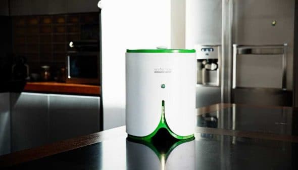 Compact white and green kitchen appliance with a button on top, placed on a dark countertop. - Olive Oil Times