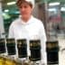 Row of olive oil bottles with green caps on a production line in a factory setting. - Olive Oil Times