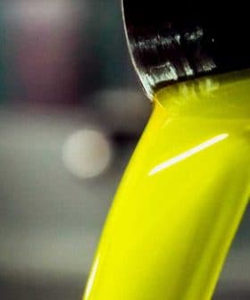 Stream of bright yellow olive oil pouring from a metal container into a bowl. - Olive Oil Times