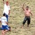Competitors in a Turkish oil wrestling match with one wrestler celebrating a victory in a grassy field. - Olive Oil Times