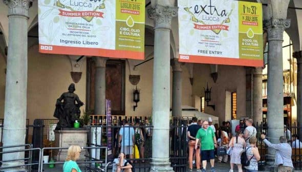 Entrance to an event in Lucca featuring large banners and people walking by. - Olive Oil Times
