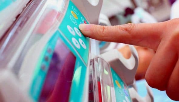 A hand pressing buttons on a medical device with a digital display in a healthcare setting. - Olive Oil Times