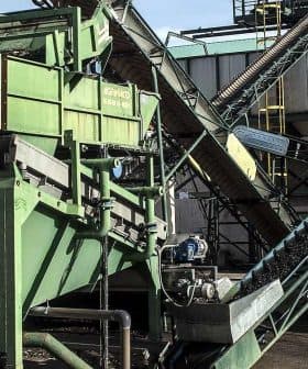 Industrial machinery for processing olives, featuring conveyor belts and a green sorting system. - Olive Oil Times