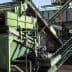 Industrial machinery for processing olives, featuring conveyor belts and a green sorting system. - Olive Oil Times