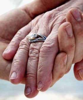 Close-up of two hands holding each other, one adorned with a silver ring. - Olive Oil Times