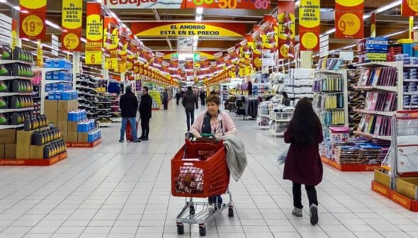 View of a supermarket aisle with shoppers and various products displayed on shelves. - Olive Oil Times