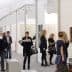 People walking through an art gallery exhibition with various artworks displayed on the walls. - Olive Oil Times