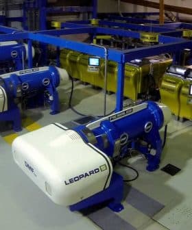 Industrial olive oil production equipment with blue and yellow machines in a processing facility. - Olive Oil Times