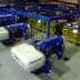 Industrial olive oil production equipment with blue and yellow machines in a processing facility. - Olive Oil Times