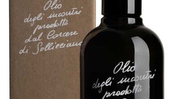 Black glass bottle of olive oil with a cardboard box featuring handwritten text. - Olive Oil Times