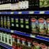 A supermarket shelf displaying various brands of olive oil in bottles and cartons. - Olive Oil Times