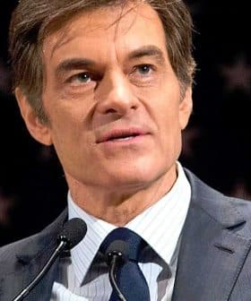 Man in a suit speaking at a podium with a microphone against a backdrop of stars. - Olive Oil Times